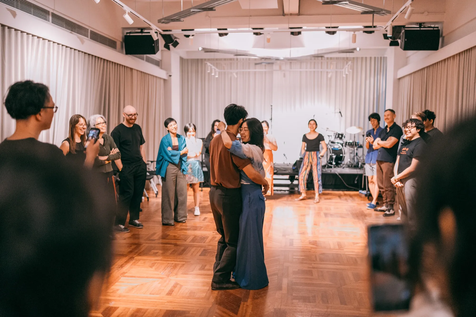Penny & Lucas dancing a demo inside a circle of smiling workshop students